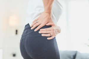 Woman holding lower back and hip area while experiencing SI joint or hip pain in Augusta, GA